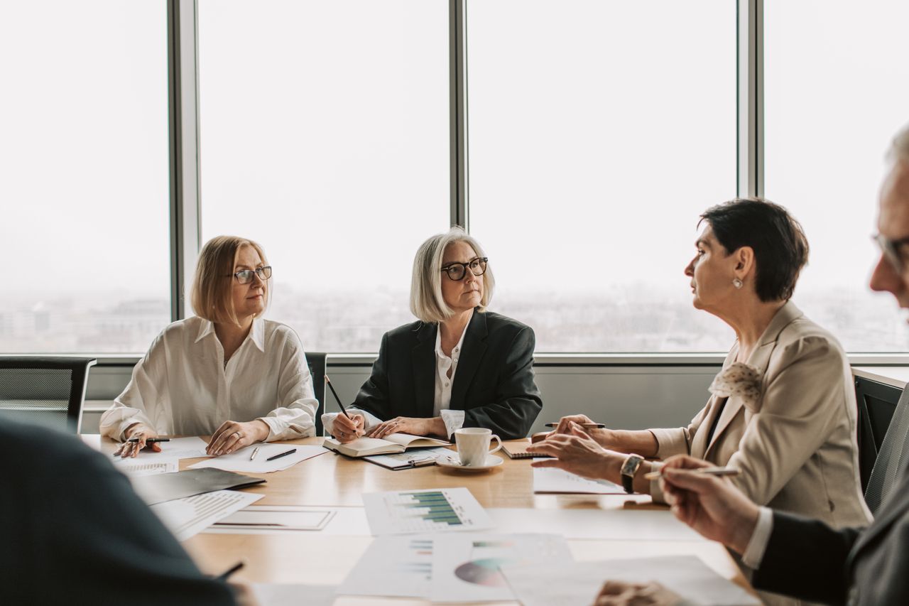 A group of senior executives engaged in a serious business meeting in a modern office setting.